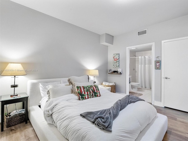 bedroom with connected bathroom and light wood-type flooring