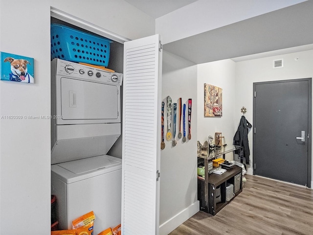 laundry area with stacked washer and dryer and hardwood / wood-style floors