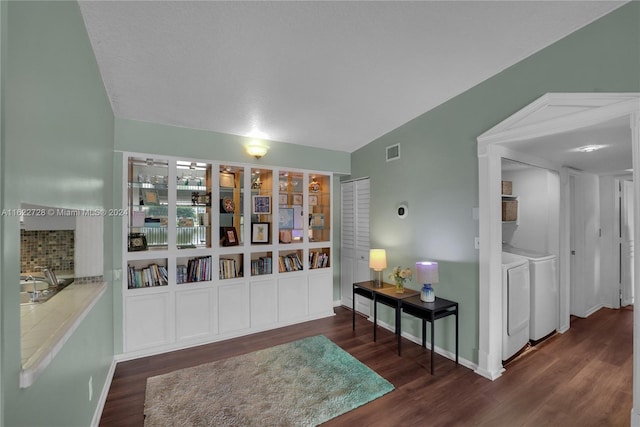 sitting room featuring built in shelves, independent washer and dryer, and dark hardwood / wood-style floors