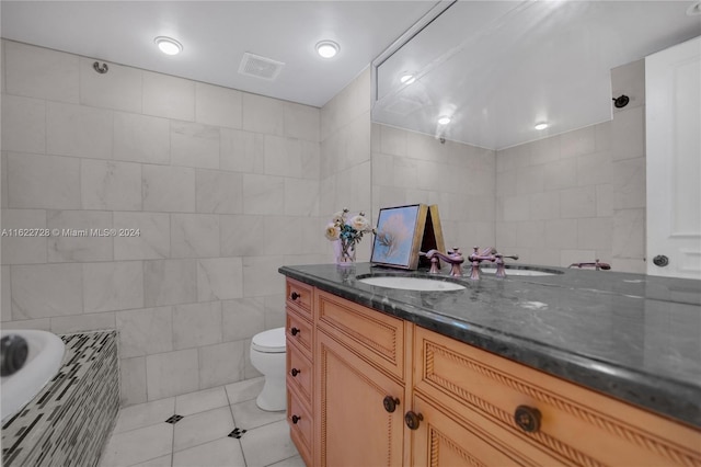 bathroom with toilet, vanity, tile patterned flooring, and tile walls