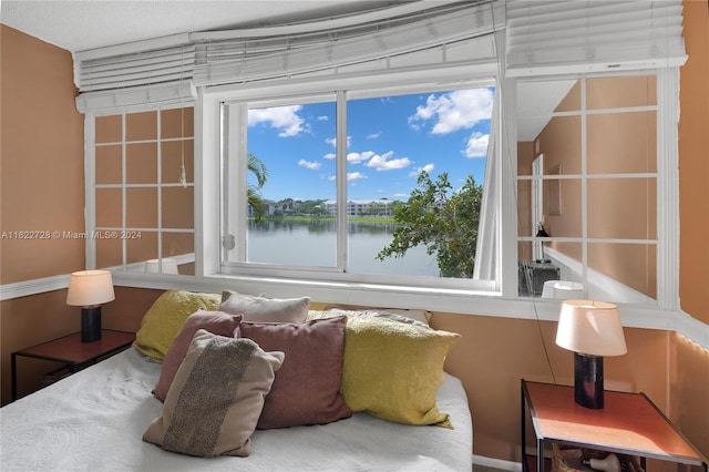 bedroom with a water view and multiple windows