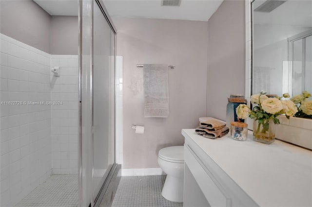 bathroom featuring tile patterned flooring, a shower with shower door, toilet, and vanity