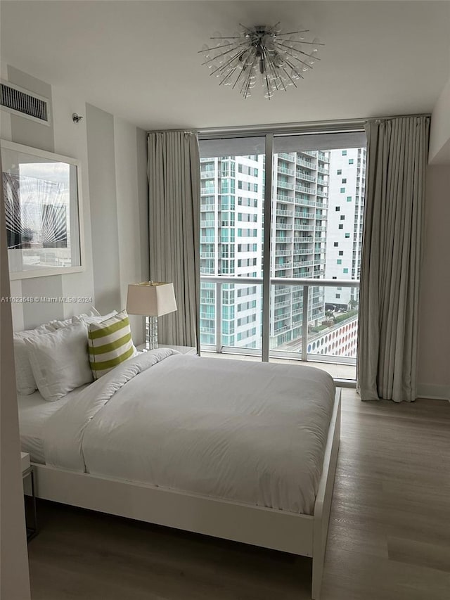 bedroom with access to exterior, multiple windows, and hardwood / wood-style flooring