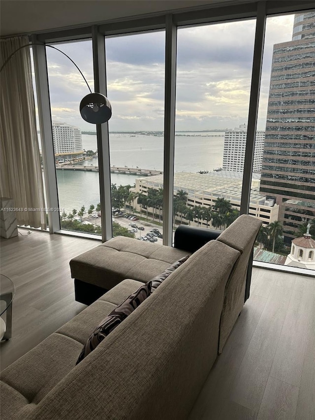 living room featuring a wall of windows, a water view, and hardwood / wood-style floors