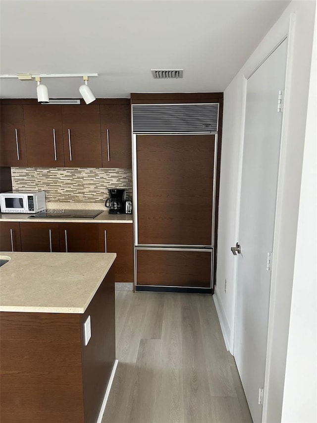 kitchen featuring light hardwood / wood-style flooring, dark brown cabinets, rail lighting, decorative backsplash, and black cooktop