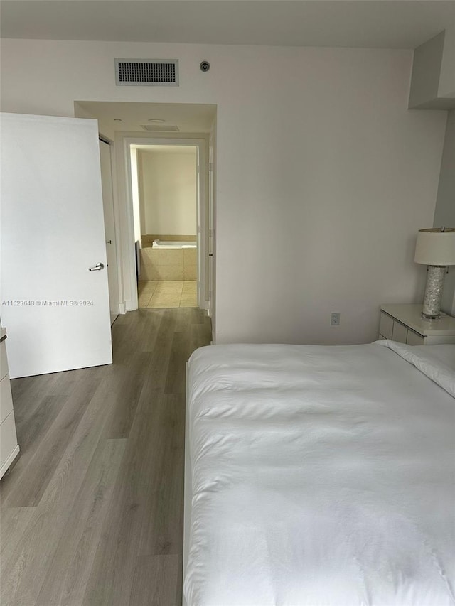 bedroom featuring ensuite bathroom and hardwood / wood-style flooring