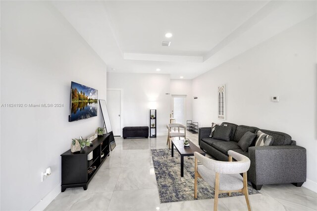 tiled living room featuring a raised ceiling