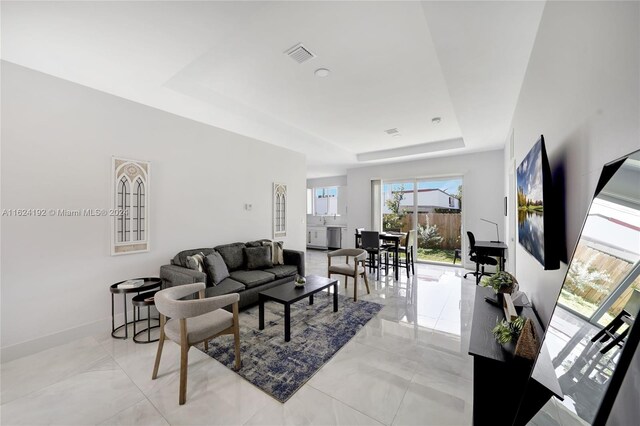 tiled living room featuring a raised ceiling