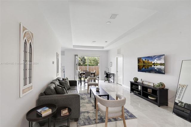 living room featuring light tile patterned flooring and a tray ceiling