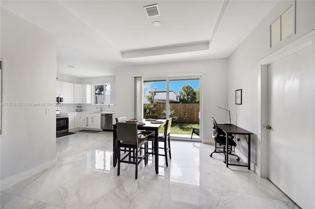 tiled dining area with sink and a raised ceiling