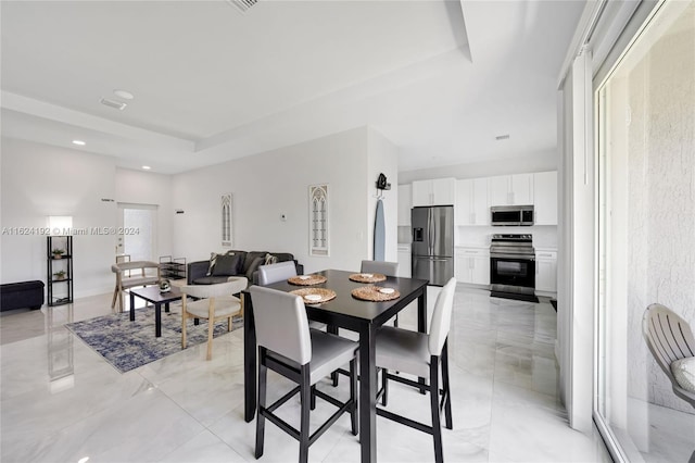 dining area featuring light tile patterned flooring and a raised ceiling