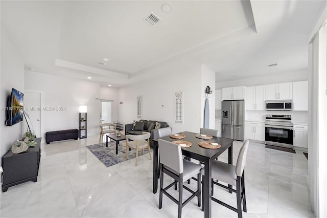 dining space with a tray ceiling and light tile patterned floors