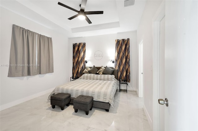 bedroom with ceiling fan, a raised ceiling, and light tile patterned floors