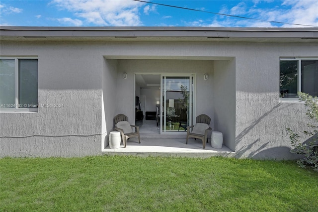 entrance to property with a patio area and a lawn