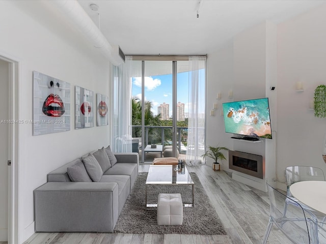 living room featuring a wall of windows and light hardwood / wood-style flooring