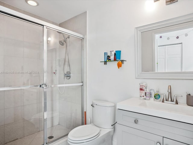 bathroom with vanity, a shower with door, and toilet
