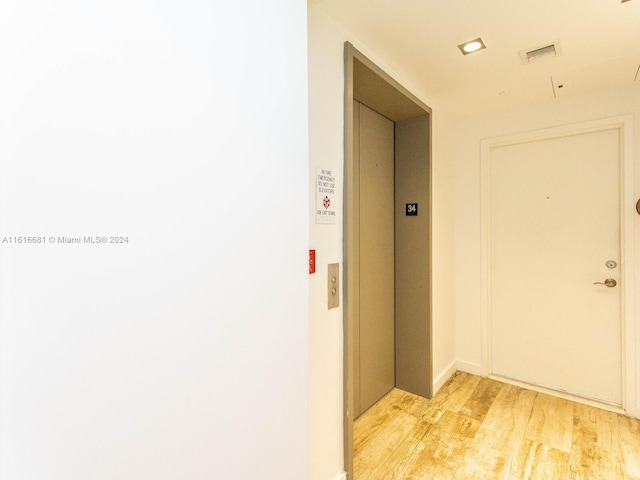 hall with elevator and light wood-type flooring