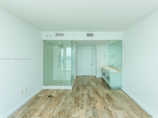 bathroom with wood-type flooring, a shower with door, and vanity