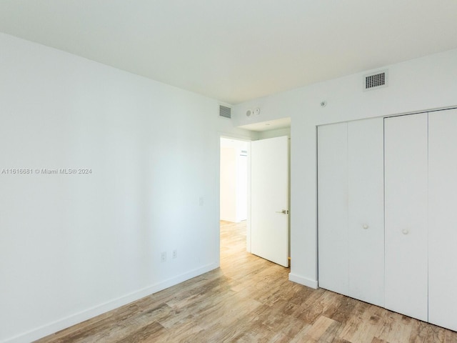 unfurnished bedroom with light hardwood / wood-style flooring and a closet