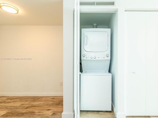 clothes washing area featuring stacked washer / drying machine and light wood-type flooring
