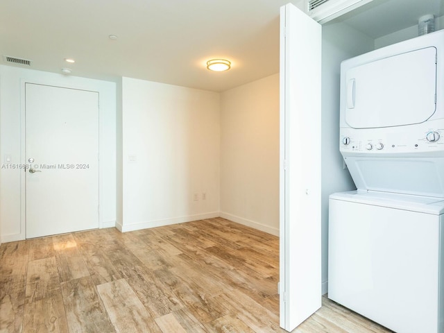 laundry area featuring stacked washer and clothes dryer and light wood-type flooring