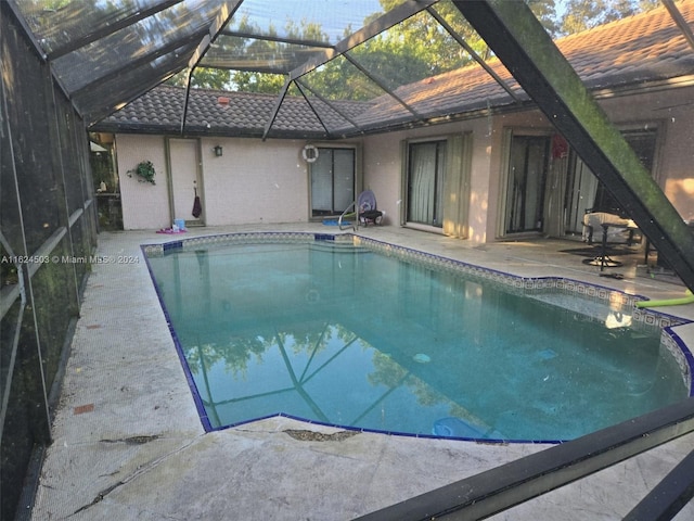 view of pool featuring glass enclosure and a patio area