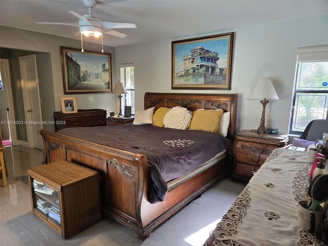 bedroom with ceiling fan, light tile patterned floors, and a textured ceiling