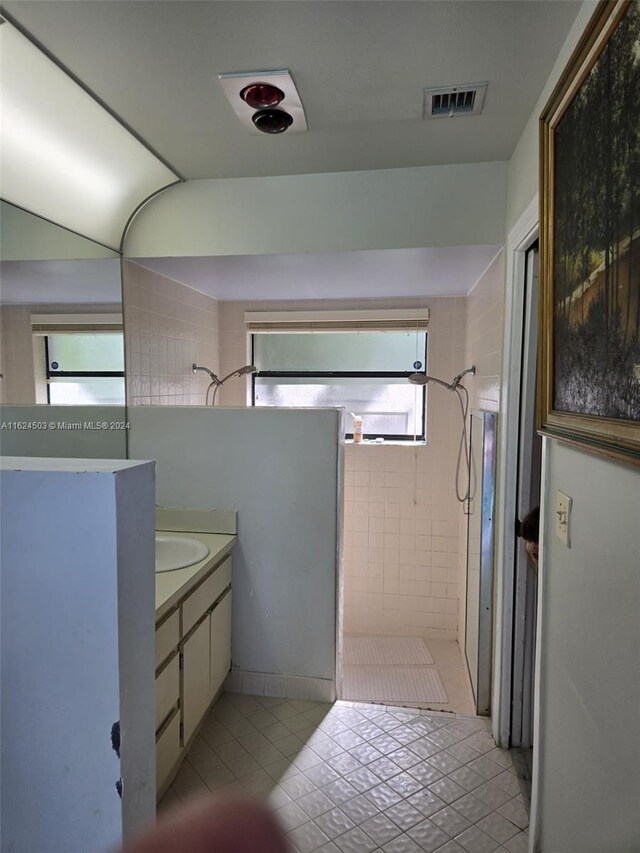 bathroom featuring a shower, vanity, tile patterned floors, and a healthy amount of sunlight