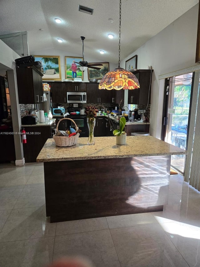 kitchen featuring a center island with sink, vaulted ceiling, a textured ceiling, tasteful backsplash, and stainless steel appliances