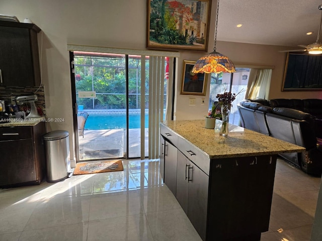 kitchen featuring decorative light fixtures, a center island, light stone countertops, and a textured ceiling