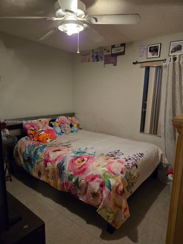 tiled bedroom with ceiling fan and a textured ceiling