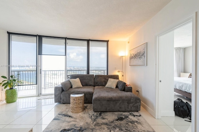 living room featuring floor to ceiling windows, light tile patterned floors, a water view, and a healthy amount of sunlight