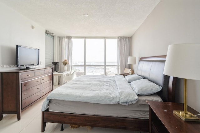 bedroom featuring a textured ceiling, light tile patterned floors, and floor to ceiling windows