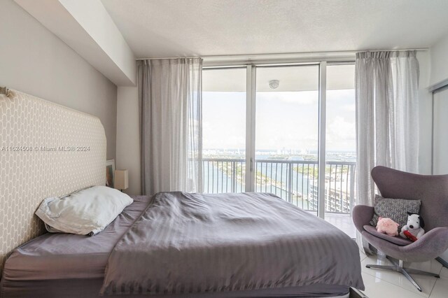 bedroom featuring access to exterior, multiple windows, a wall of windows, and a water view