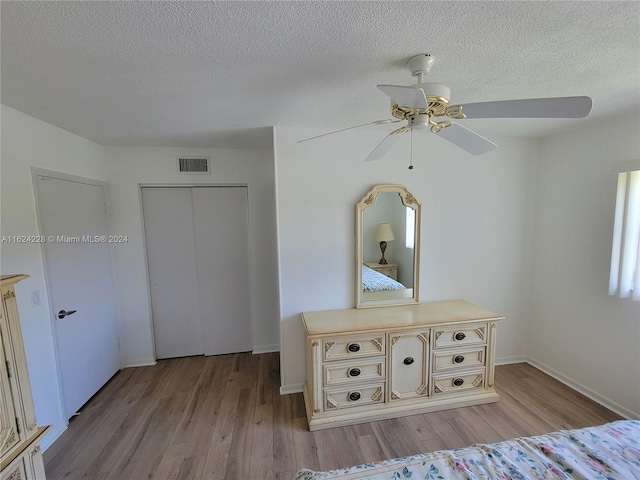 unfurnished bedroom featuring a closet, ceiling fan, light hardwood / wood-style floors, and a textured ceiling