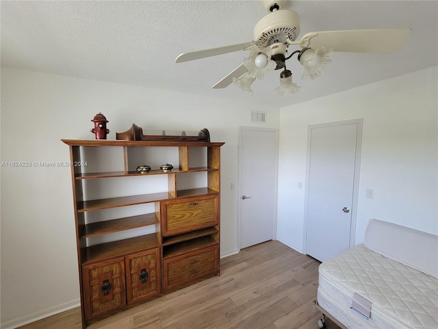 bedroom featuring ceiling fan, a textured ceiling, and light hardwood / wood-style flooring