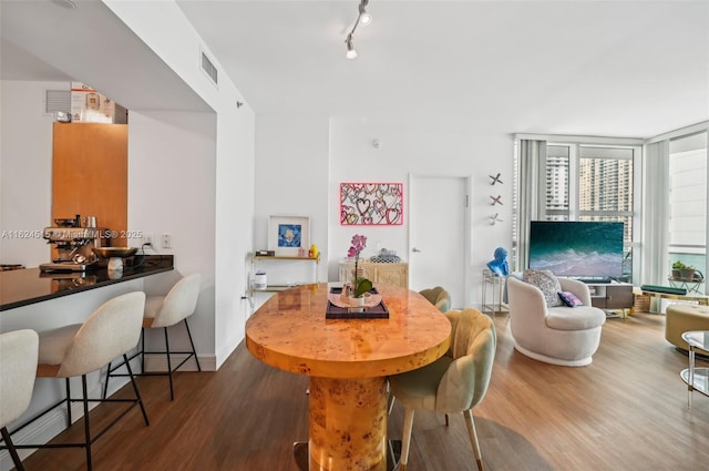 dining area featuring floor to ceiling windows, hardwood / wood-style floors, and track lighting