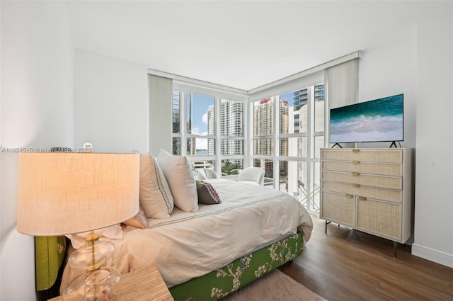 bedroom with dark hardwood / wood-style floors and a wall of windows