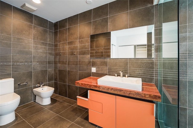 bathroom with a bidet, tile patterned floors, tile walls, toilet, and vanity