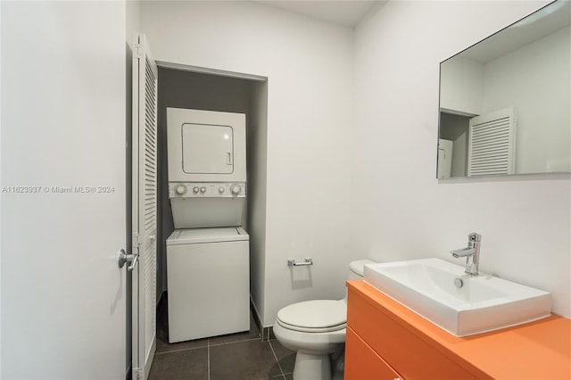 bathroom featuring toilet, tile patterned flooring, stacked washer and dryer, and vanity