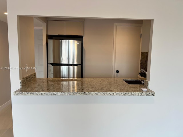 6580 W Flagler St Unit 309, Miami, FL 33144 - kitchen featuring gray cabinets, light stone countertops, a sink, freestanding refrigerator, and a peninsula