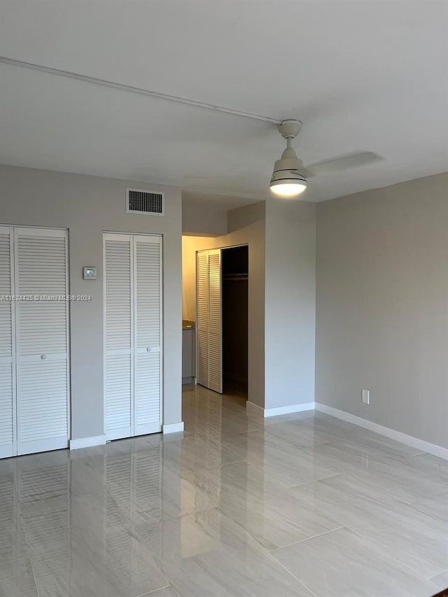 interior space with multiple closets, ceiling fan, and light tile patterned floors