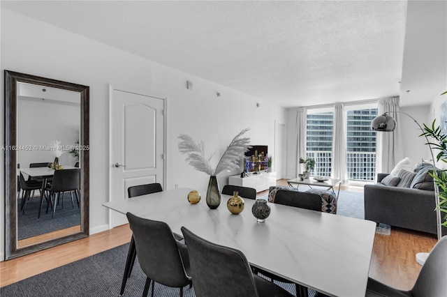 dining space with a textured ceiling, hardwood / wood-style flooring, and expansive windows