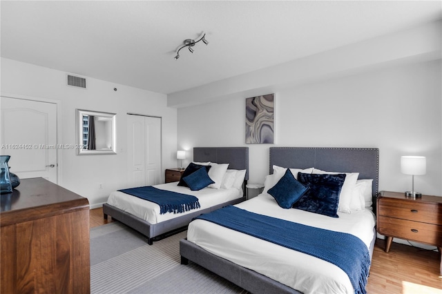 bedroom with rail lighting, a closet, and hardwood / wood-style flooring