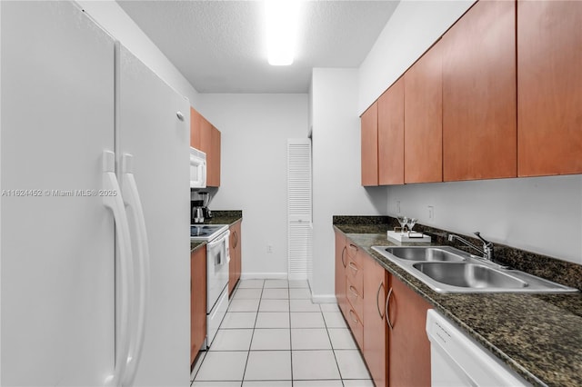 kitchen with dark stone countertops, sink, white appliances, light tile patterned flooring, and a textured ceiling