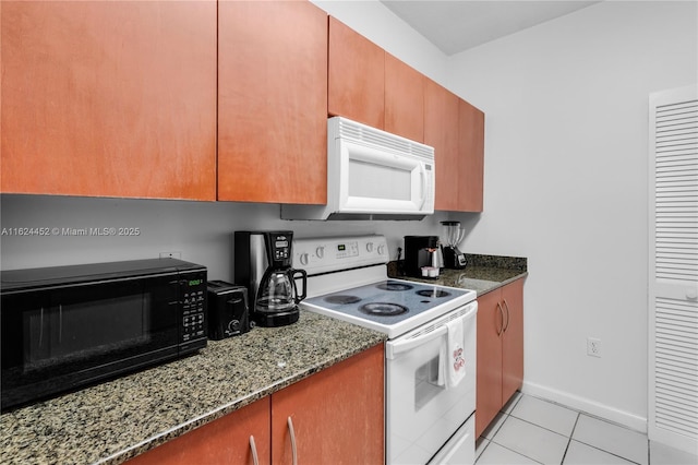 kitchen featuring light tile patterned floors, dark stone countertops, and white appliances