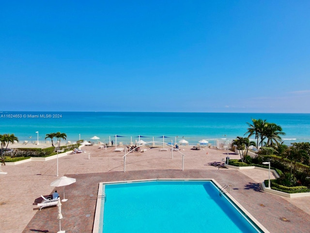 view of swimming pool with a water view and a beach view