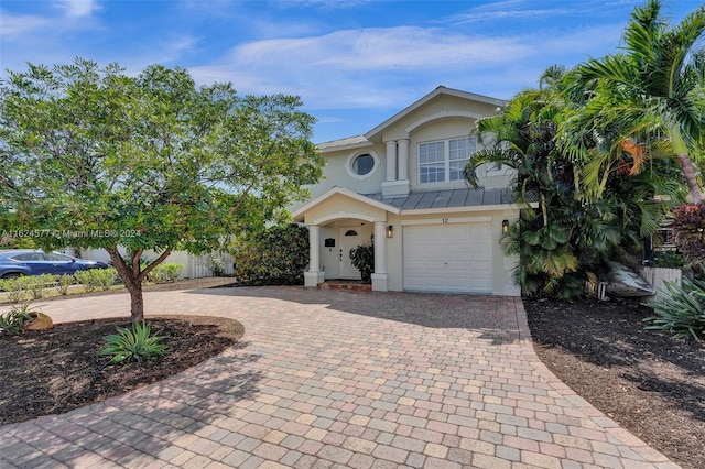 view of front of property featuring stucco siding, an attached garage, and decorative driveway