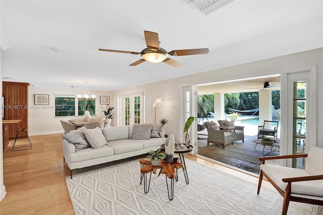 living room with light hardwood / wood-style flooring, ceiling fan with notable chandelier, and plenty of natural light