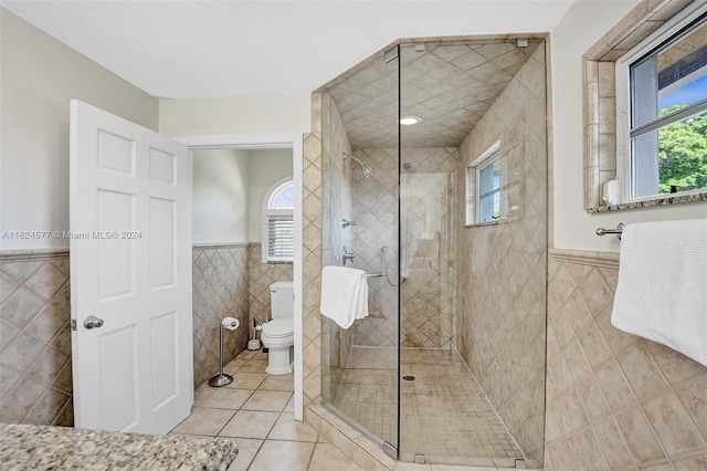 bathroom with a shower with shower door, toilet, tile patterned flooring, and tile walls